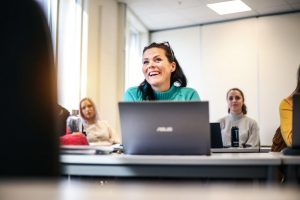 Bilde av en elev ved fagskolen som følger med på undervisning på en skolepult med en PC foran seg