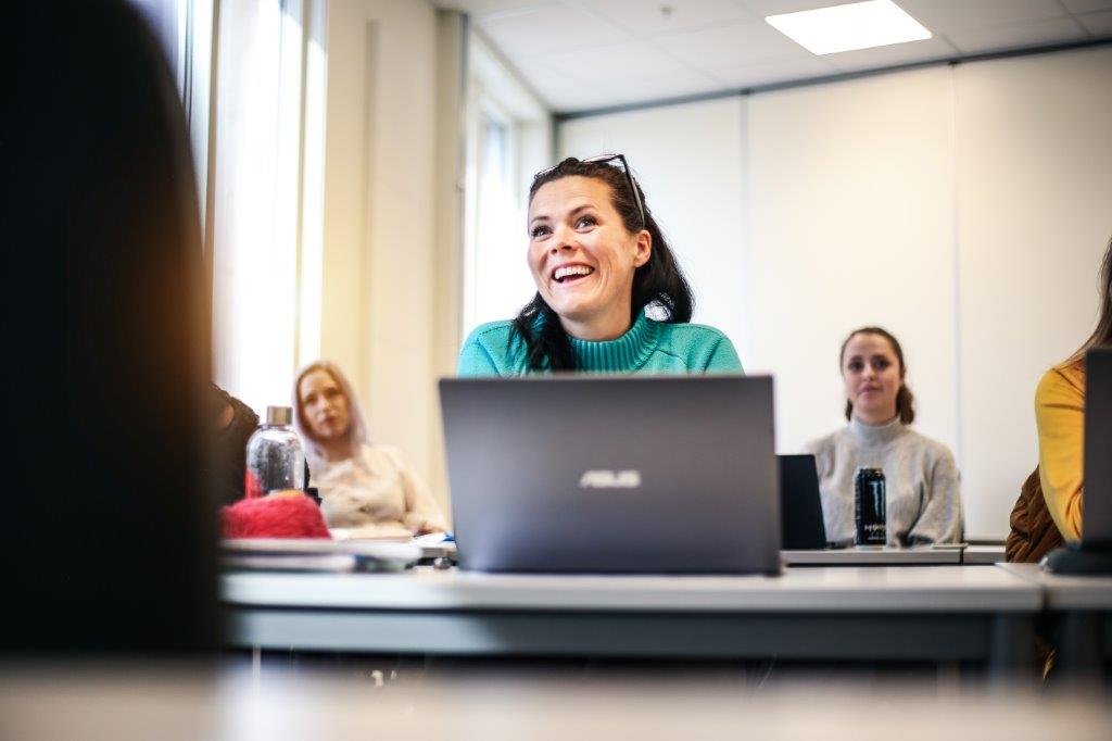 Bilde av en elev ved fagskolen som følger med på undervisning på en skolepult med en PC foran seg