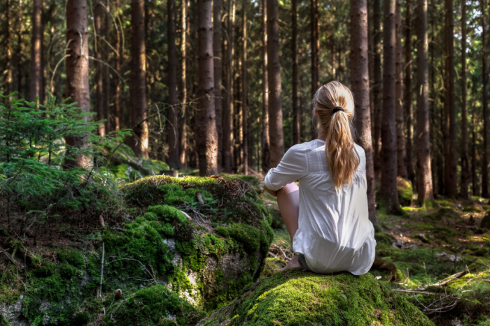 Foto av kvinne som sitter i grønn skog