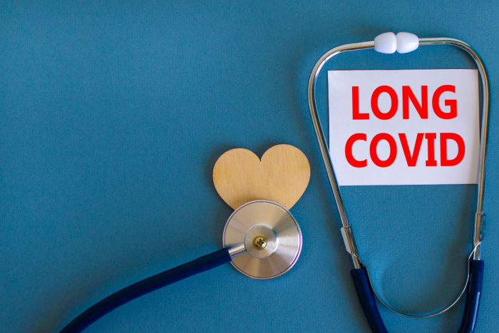 COVID-19 pandemi long covid symbol. Hvitt kort med ordet long covid, blå bakgrunn, tre hjerte og stetoskop.