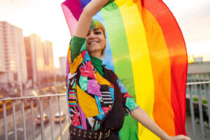Blond dame som holder et regnbueflagg