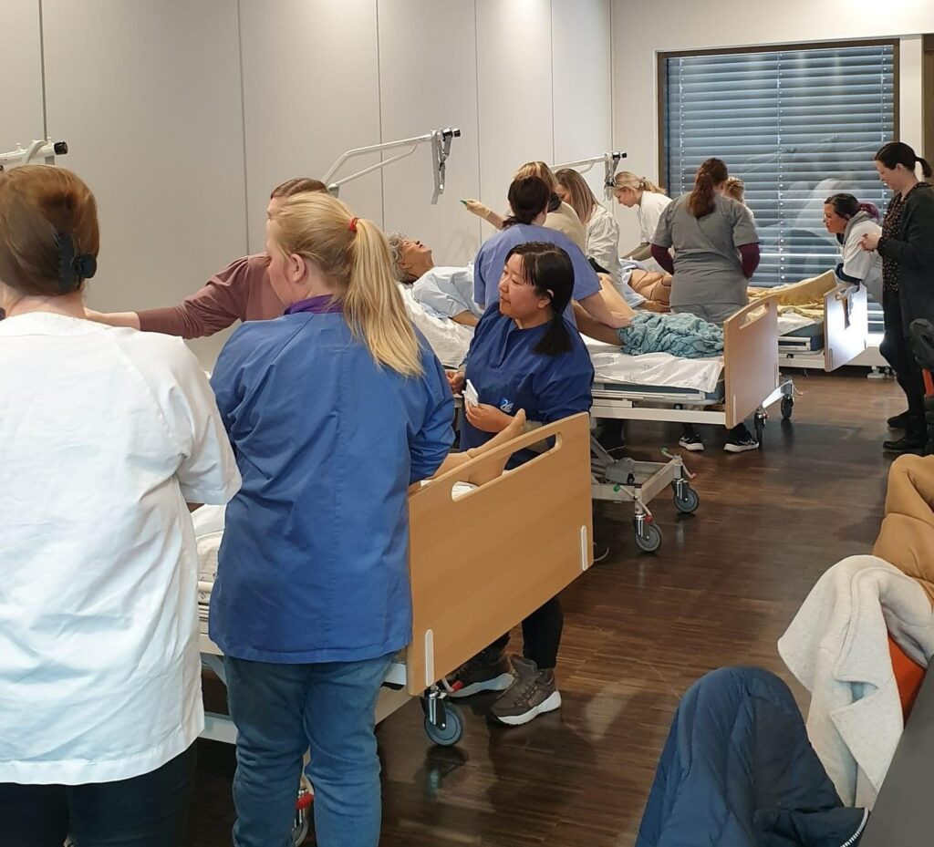 Helsepersonell står rundt senger og simulerer situasjoner.