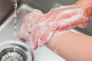 Person vasker hendene med såpe og vann