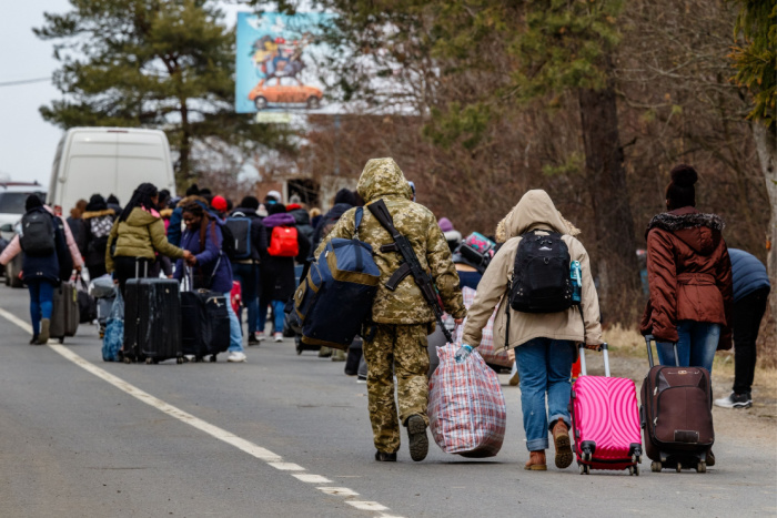 Ukrainske flyktninger med bagasje som er på vei over grensen