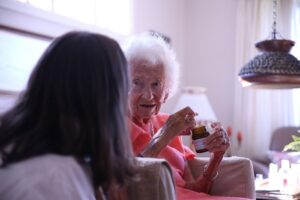 Fotografi av geriater Marte Wang-Hansen i samtale med en eldre dame.