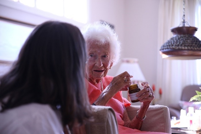 Fotografi av geriater Marte Wang-Hansen i samtale med en eldre dame.