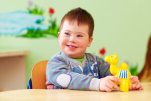 Gutt med Downs syndrom leker med gul plastikkleke