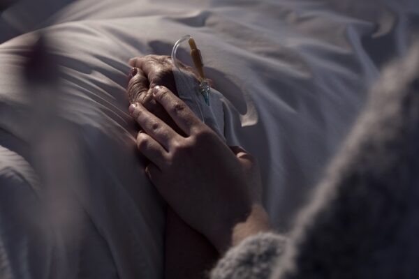 To stykker som holder hverandre i hendene i en sykeseng