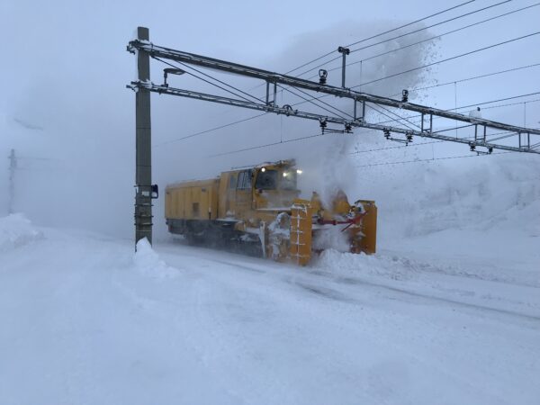 Fotografi av et tog som måker skinnene i snøstorm