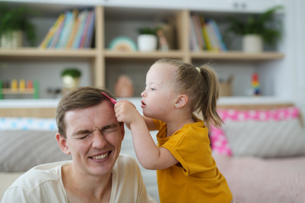 A,Child,With,Down,Syndrome,Plays,With,Dad,,Daughter,Takes Fotografi av ung gutt og liten jente med down syndrom
