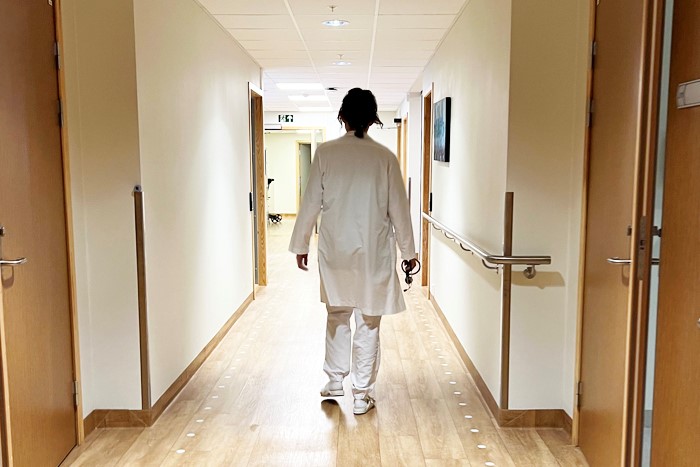 Lege som går i hvit frakk i gangen på et sykehjem