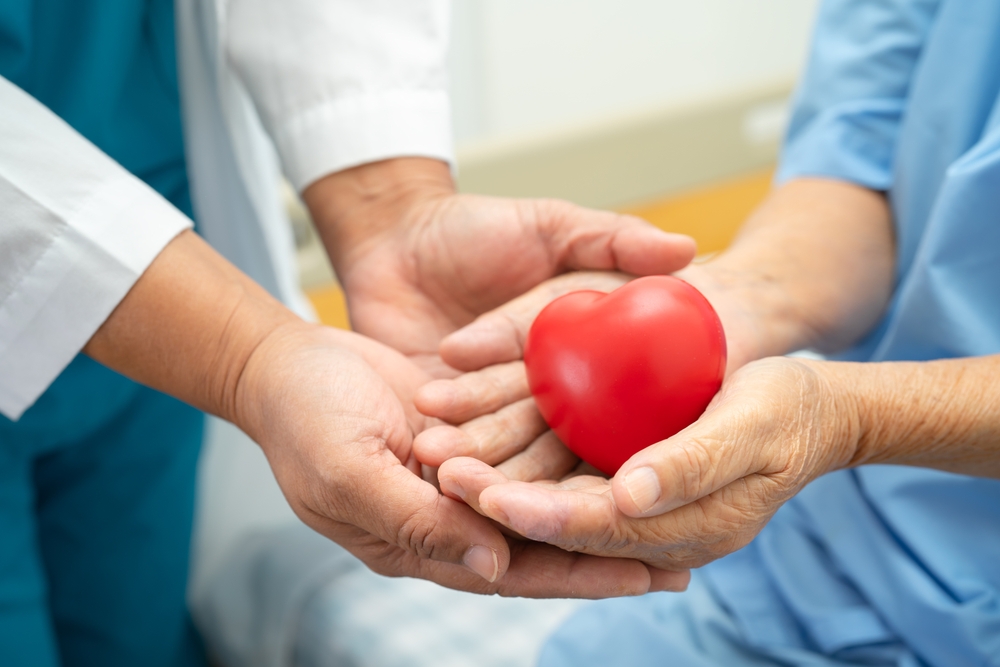 Doctor,Give,Red,Heart,To,Asian,Elderly,Woman,Patient,In Fotografi av helsepersonell som overleverer en hjerte-figur over i hendene til en pasient, på sengekanten.