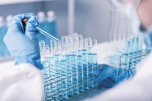 Forsker som drypper kjemisk væske i reagensglass