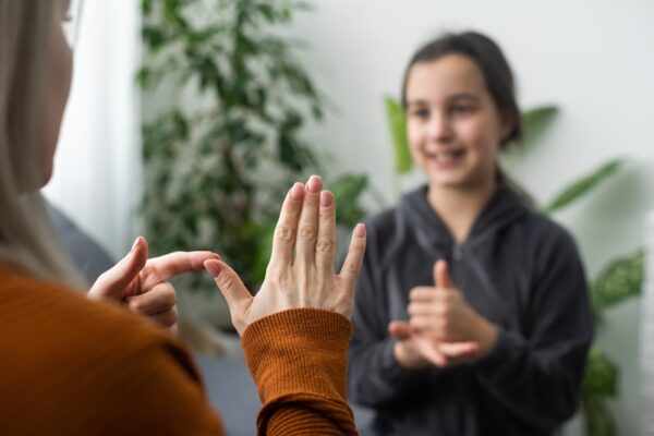 Fotografi av to to jenter som kommuniserer via tegnspråk