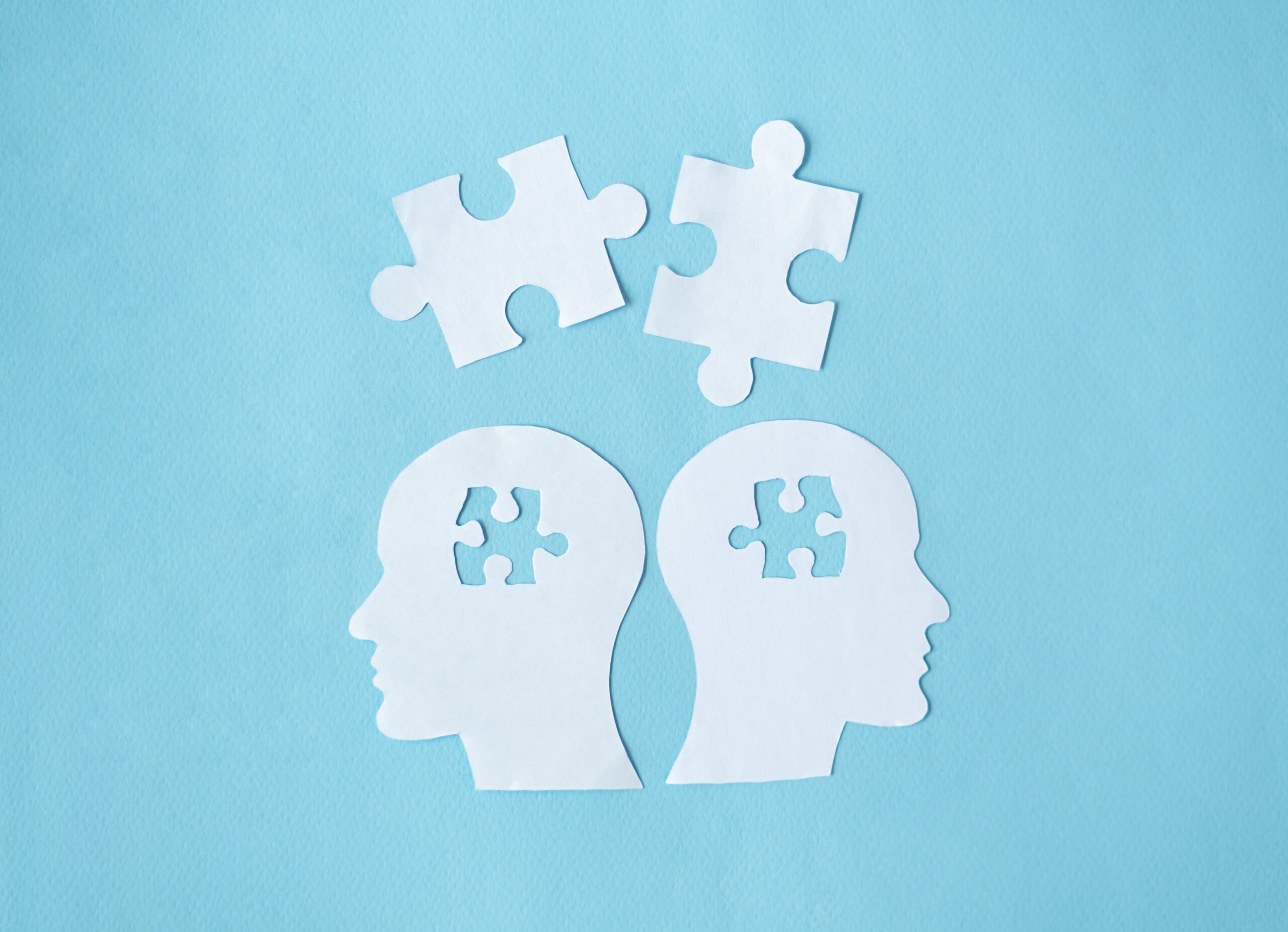 Paper,Head,With,Puzzle,Pieces,Autism,Concept.,Blue,Background Illustrasjon av hoder i papir, mangler en puslebrikke fra hodene deres, blå bakgrunn