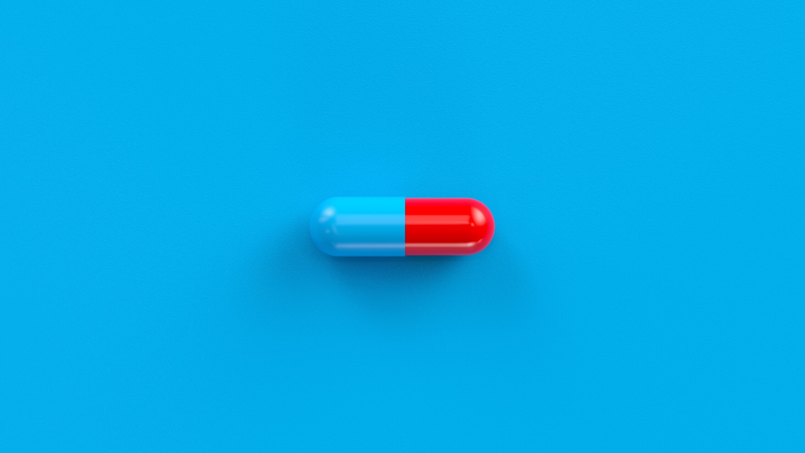Blue,Red,Single,Pill,Isolated,On,A,Blue,Background.,Tablet, Fotografi av blå/rød pille liggende på blå bakgrunn