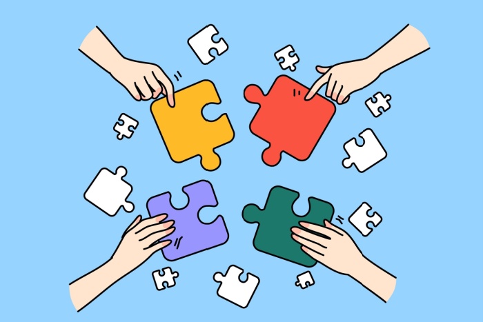 Illustrasjonsbilde som viser fire puslespillbrikker i ulike farger med en hånd på hver bit, illustrerende for samarbeid.