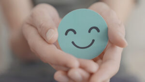 Hender som holder en grønn smiley