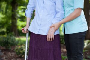 Helsepersonell støtter kvinnelig pasient med krykke. Foto: shutterstock