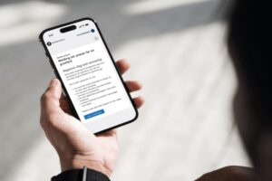 Bildet viser en hånd som holder en telefon med informasjonssiden til melding om ansvar for en gravferd.