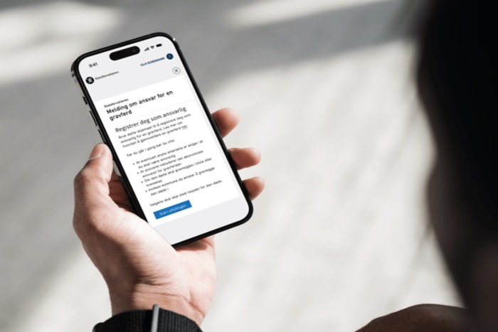 Bildet viser en hånd som holder en telefon med informasjonssiden til melding om ansvar for en gravferd.