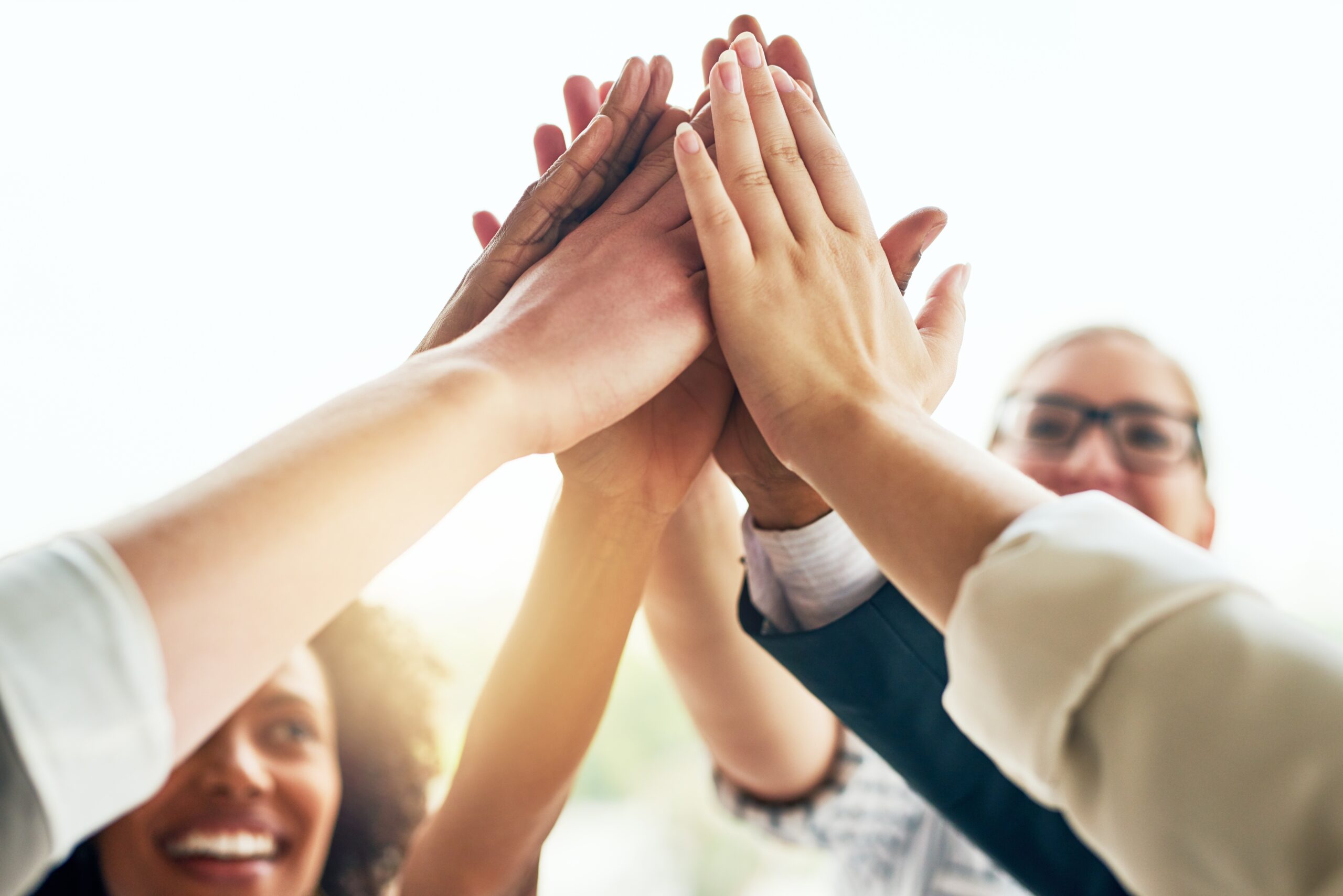 Business,,People,And,Happy,With,High,Five,At,Office,For Fotografi av en gruppe mennesker som "High-fiver" hverandre samtidig. Litt sollys slipper til mellom armene. Lykkelig gjeng