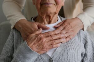 Eldre person som legger hånden sin oppå hendene til en person som holder rundt den.