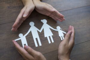 Hender som favner om papirutklipp som symboliserer familie