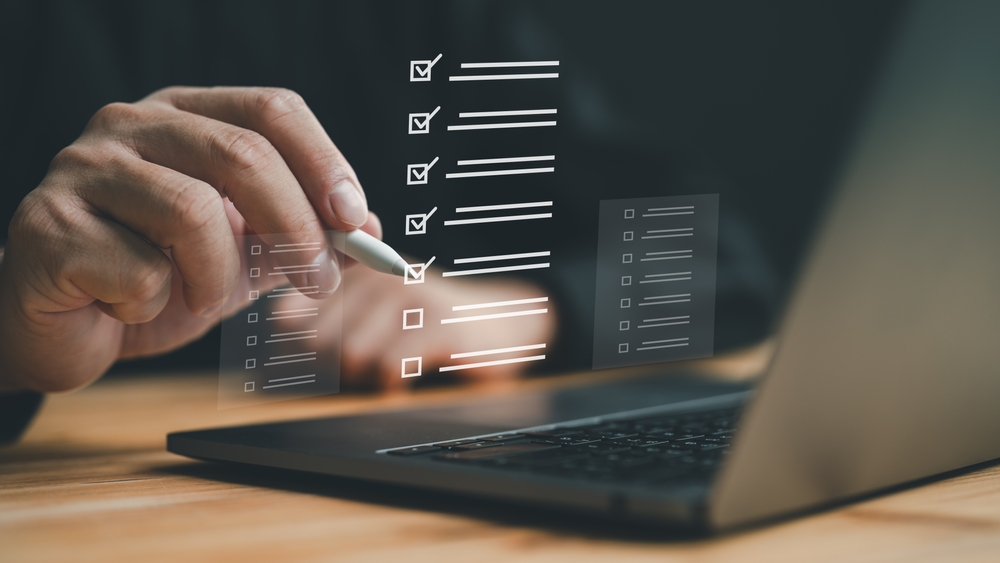 Business,Performance,Checklist,,Businessman,Doing,Online,Checklist,Survey,,Filling,Out Bildeillustrasjon av en hånd som holder digital penn opp foran laptop, og huker av en liste bokser