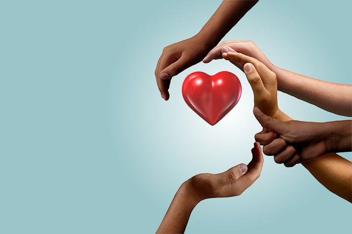 shutterstock_1545794768-kopi_KB hender som omfavner et hjerte med blå bakgrunn