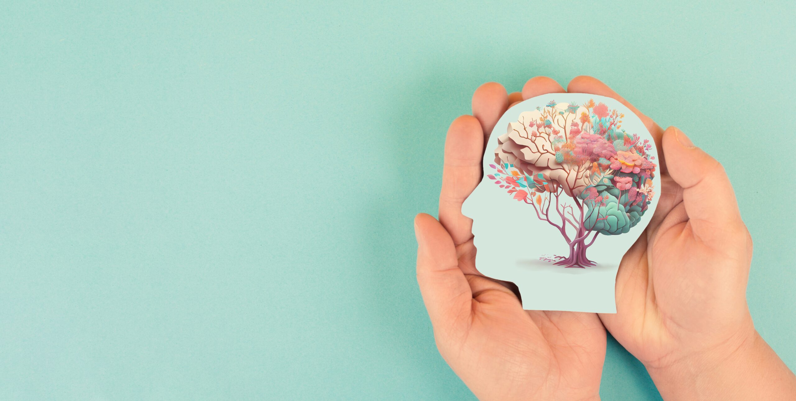 Hands,Holding,Head,,Human,Brain,With,Flowers,,Self,Care,And fotografi av to hender som holde på et utklipp av et mennesekhode i profil. I hodet er det illustrsjoner av blader / natur-bevegelser. Turkis bakgrunn