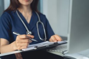 Foto av kvinnelig lege som skriver på et papir, ment å illustrere papirrekvisisjon.