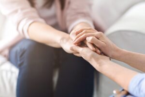 Hender som omsorgsfullt holder rundt en annens hender.