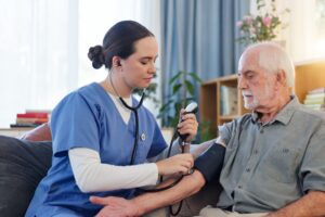 Pleier måler blodtrykk på eldre mann.