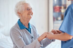 Eldre kvinne som holder i hendene til en pleier.