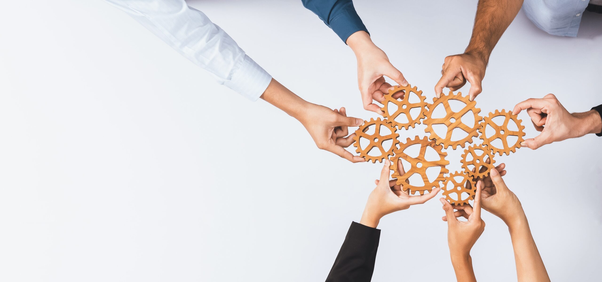 Flere hender holder et tannhjul. Visualiserer å holde tannhjulene i gang. Teamwork.