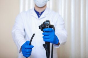 Illustrasjonsbilde av hvitkledd mannlig helsepersonell som holder et endoskop.