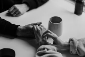 To som holder hender mens de sitter på hver sin side av bordet