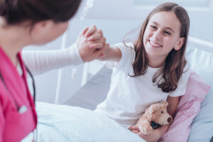 Bilder viser en jungdomsjente som smiler å holder hånden til en helsepersonell.