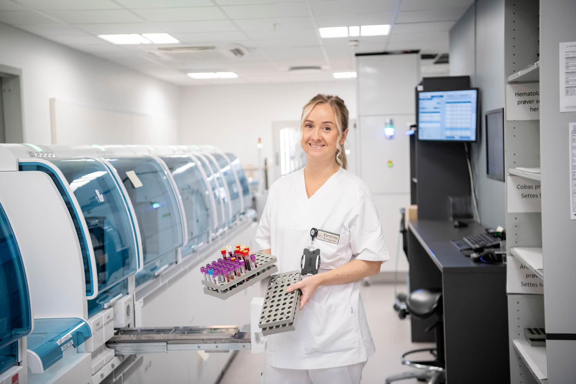 Fotografi av helsepersonell i lab på Sykehuset i Vestfold, holder rekvisitter og smiler til kamera i kledd uniform
