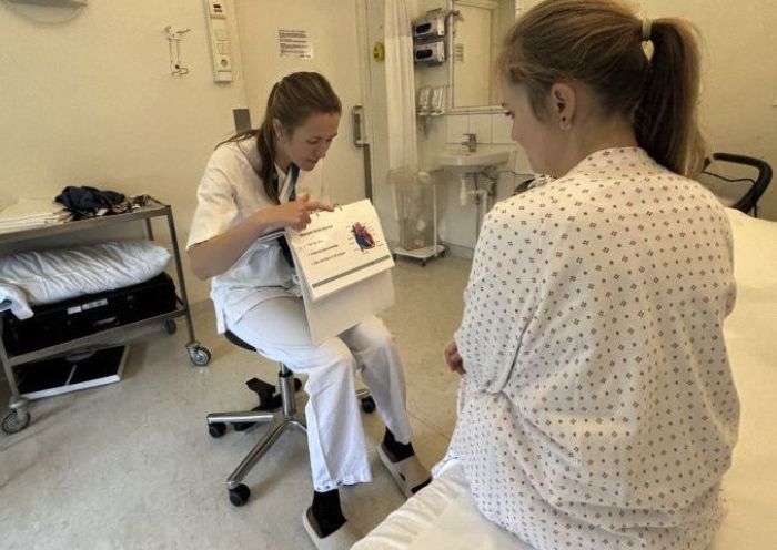 Sykepleier som viser pasient en brosjyre