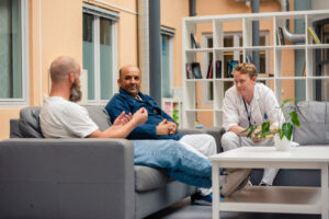 fotografi av tre menn i samtale foran et publikum, seminar-panel-situasjon