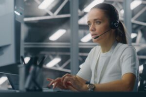 Illustrasjonsbilde av kvinne sittende forran skjerm med headsett på. Ment å illustrere akuttmedisinsk kommunikasjonssentral(AMK).