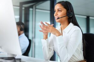 Ilustrasjonsbilde av kvinne med headset på sittende å se på en dataskjerm.