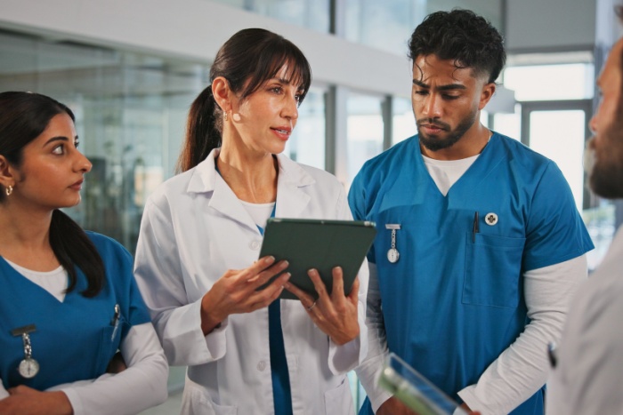 Helsepersonell som står sammen og snakket med tablet i hånden