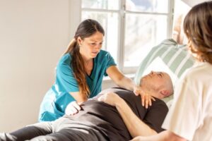 Helsepersonell som hjelper pasient som ligger i sengen