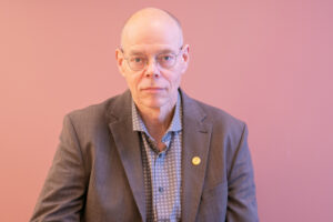 Fotografi av Edwin Schei foran rosa vegg