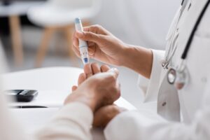 Foto: Shutterstock, Lege som tar blodprøve av en pasients fingertupp