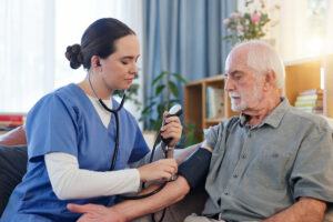 Helsearbeider som måler blodtrykk til eldre mann.