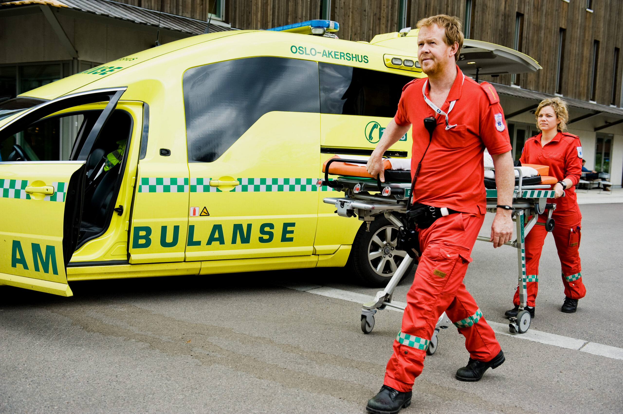 Ambulanse og helsepersonell på utsiden av ambulansen med en båre.